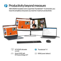 34-inch curved widescreen monitor displaying video conference, paired with wireless keyboard, mouse, and two laptops.