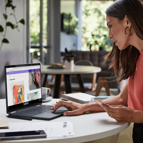 Blue HP Elite Dragonfly laptop open on white table with woman using touchscreen in bright room.