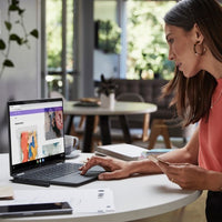 Blue HP Elite Dragonfly laptop open on white table with woman using touchscreen in bright room.
