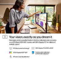 34-inch ultra-wide HP monitor on desk displaying colorful graphs and charts next to woman adjusting screen angle.