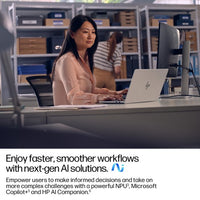 Silver HP EliteBook 14-inch laptop open on a desk with a woman working at it in an office setting.