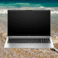 Silver HP ProBook 455 G10 laptop open showing black keyboard and blank 15.6-inch screen on a sandy beach background.